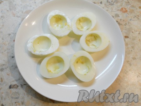 Вареные яйца очистить, разрезать на 2 части. Отделить белки от желтков. Белки выложить на тарелку.