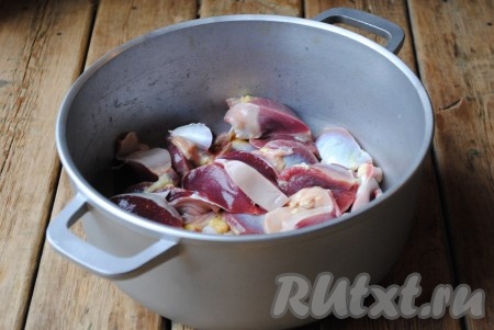 Куриные желудочки вымыть и нарезать небольшими кусочками, а затем выложить в сковороду или казан. Добавить растительное масло. 