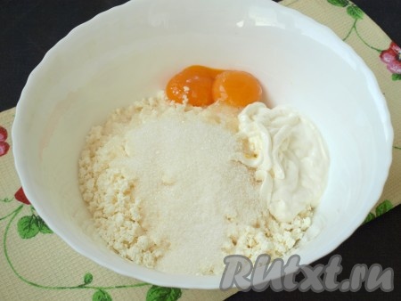 Яйца аккуратно разделить на белки и желтки. В глубокую миску высыпать творог и хорошо размять, добавить половину сахара, ванильный сахар, сметану и желтки. Белки убрать на время в холод.

