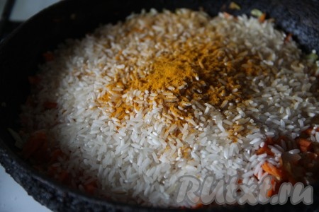 Добавить к обжаренным овощам рис и куркуму, тщательно перемешать.
