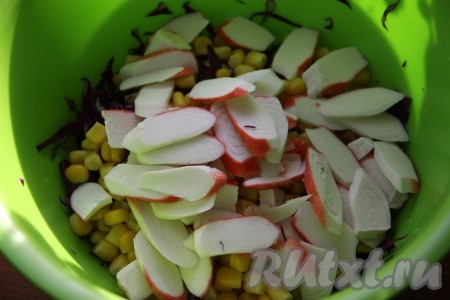Добавить в салат из краснокочанной капусты и кукурузы нарезанные произвольным образом крабовые палочки.
