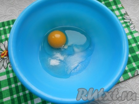 В миску разбить сырое яйцо, добавить соль и сахар.
