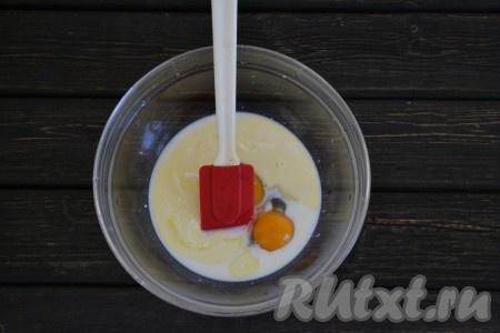 В миске соединить теплое молоко, растаявшее сливочное масло и яйца. 