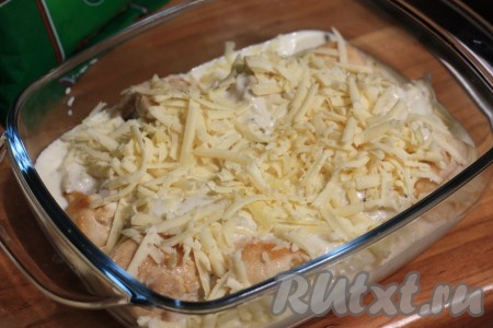 В форму для запекания выложить обжаренную курицу, залить сливочно-чесночным соусом, посыпать натёртым сыром.

