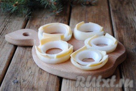 Затем между кольцами выложить сыр, предварительно нарезав его тонкими пластинками. 