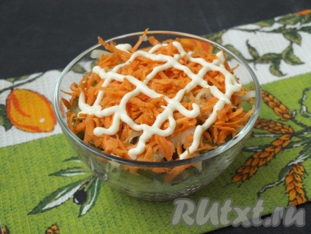 Сырую морковь натереть на средней тёрке и выложить поверх лука. На слой моркови нанести сеточку из майонеза.
