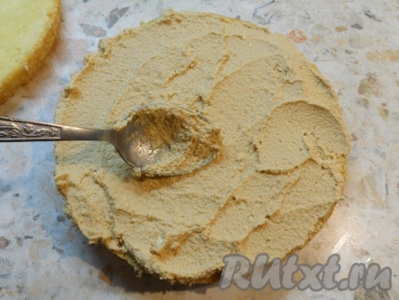 Смазать половиной крема нижнюю часть бисквита.