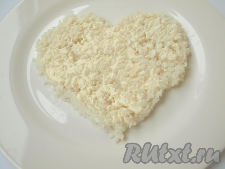 На плоскую тарелку выложить варёный рис, придавая ему форму сердца, немного смазать рис майонезом.
