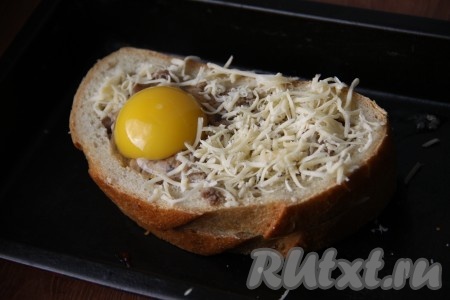 Сверху бутерброда с фаршем аккуратно разбиваем яйцо, стараясь не повредить желток. Солим яйцо и присыпаем бутерброд тертым сыром.
