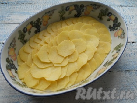 Картофель очистить и нарезать очень тонкими кружочками (для этого подойдет шинковка для капусты или специальная терка). Выложить половину картофеля внахлест в форму для запекания.