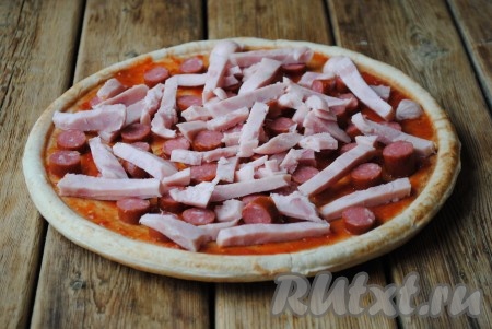 Колбасу нарезать длинными полосками и выложить на основу для пиццы. 
