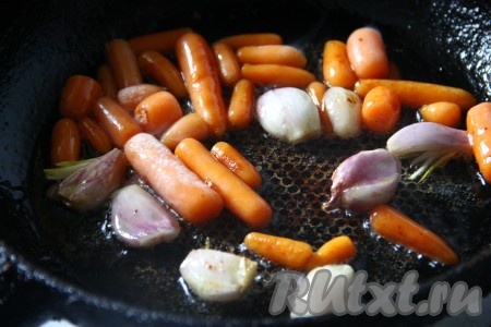 Морковь, лук и чеснок очистить. На сковороде, в которой обжаривали мясо, обжарить на среднем огне крупно нарезанную морковь, лук и целые зубчики чеснока до золотистого цвета со всех сторон.
