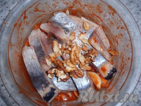 Филе сельди нарезать тонкими полосками, при необходимости удалить косточки. В приготовленную томатную заправку добавить селедку и крупно порубленные грецкие орехи.
