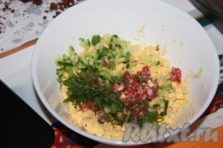 Яичные желтки растереть в мелкую крошку, добавить туда мелконарезанные огурец, колбасу и зелень.
