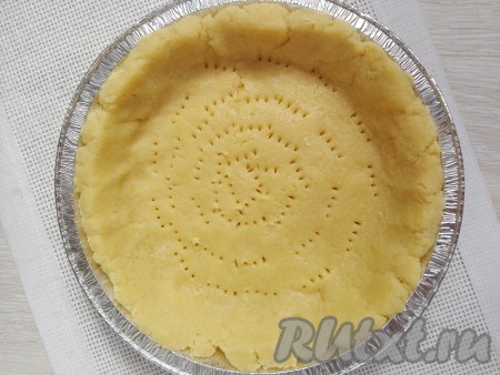 Охлаждённое тесто раскатать (используя скалку) и выложить на дно формы, застеленной пергаментом. Вилкой сделать проколы по всей площади уложенной основы пирога.
