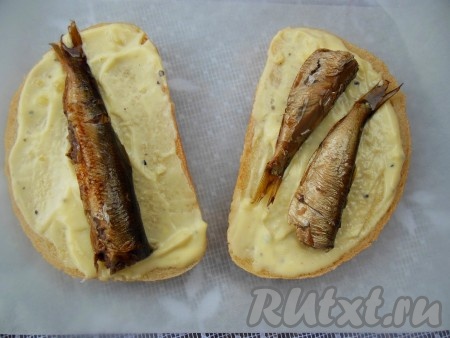 Откройте банку со шпротами, масло слейте. Если рыбка крупная, на каждый бутерброд положите по 1 рыбке, если мелкая - по 2.
