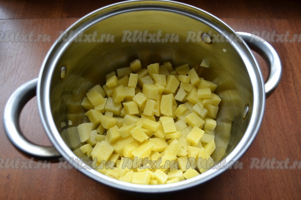 Картофель очистить и нарезать кубиками прямо в кастрюлю. Залить водой, довести до кипения, затем огонь уменьшить, посолить и варить картошку 15 минут.
