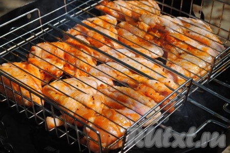 Замаринованные куриные крылья переложить на решетку-гриль. В данном рецепте решетку смазывать растительным маслом не нужно, так как в составе маринада есть масло, поэтому в процессе запекания мясо к решетке прилипать не будет. 