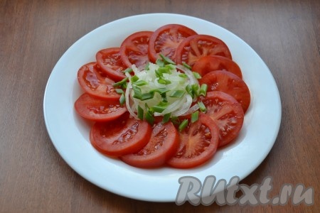 Отжатый лук разместить в центре тарелки с помидорами, сверху посыпать измельченным зеленым луком.