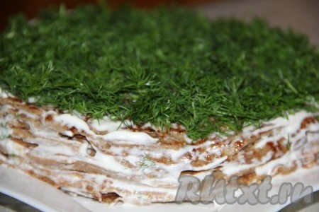 Полученные печеночные коржи смазываем майонезом и всерху украшаем торт зеленью.