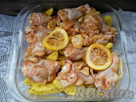 Сверху на картофель выложите куриные крылья с лимоном и чесноком, также залейте оставшимся маринадом.
