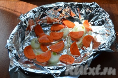 Форму для запекания застелить фольгой, влить растительное масло и разместить на дне нарезанные лук и морковь.
