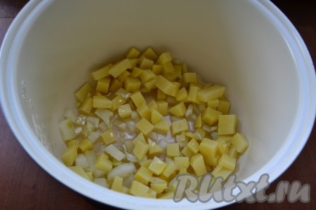 В чашу мультиварки влить растительное масло, выложить лук и картошку, выставить программу "Выпечка" на 10 минут. Обжарить овощи, периодически их помешивая.
