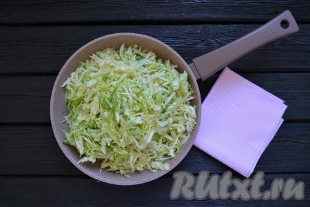 Нашинковать капусту тонкой соломкой. Разогреть сковороду с растительным маслом и выложить в нее капусту.