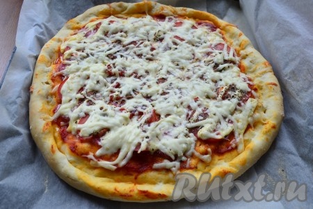 Выпекать пиццу с помидорами, колбасой и сыром в разогретой до 230 градусов духовке около 15 минут.

