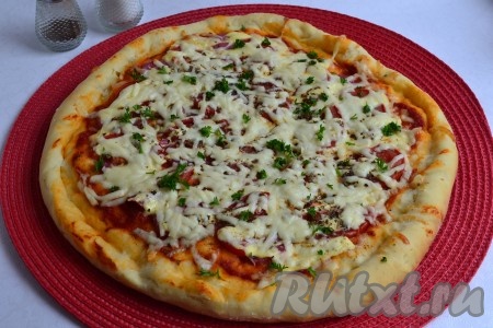 Готовую пиццу посыпать измельченной зеленью.