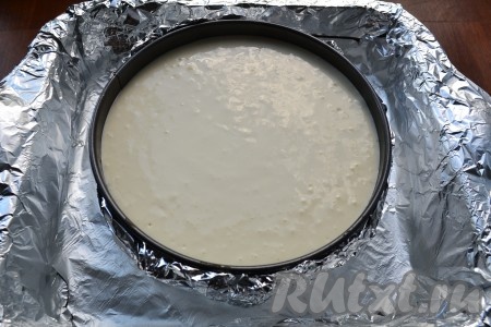 Поместить форму с чизкейком в большую по объему форму, влить горячую воду, чтобы она была до половины формы с десертом.