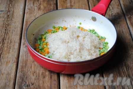Рис хорошо промыть в нескольких водах (я готовила пропаренный длиннозерный рис), затем воду слить, а рис добавить в сковороду к гороху и морковке. 
