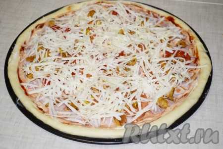 Сверху посыпать пиццу сыром, натертым на крупной терке.

