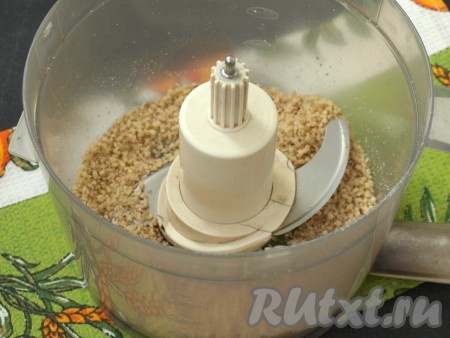 Очищенные грецкие орехи сложить в чашу комбайна и измельчить при помощи насадки "металлический нож".
