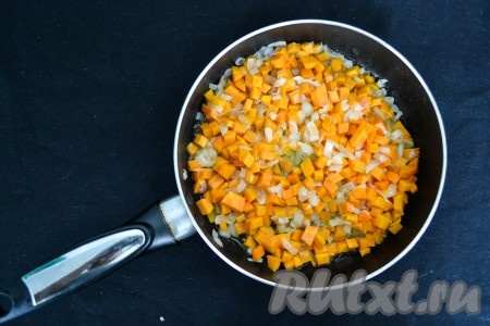 На сковороду влить растительное масло, поставить на огонь и через минуту выложить очищенные и нарезанные мелкими кубиками лук и морковь. Помешивая, обжарить их на среднем огне 2 минуты.
