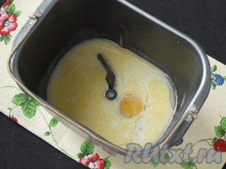 Подогреть немного молоко и перелить его в контейнер хлебопечки. Добавить растопленное остывшее сливочное масло и яйцо.
