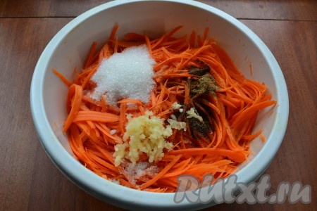 К моркови добавить соль, сахар, уксус, пропущенный через пресс чеснок, растительное масло, кориандр и черный молотый перец.

