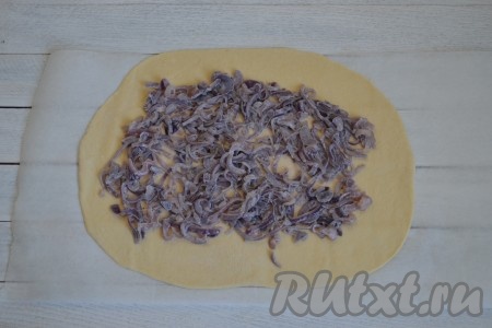 На раскатанное тесто равномерным слоем выложить луковую начинку, отступая от краёв по 2-3 см.
