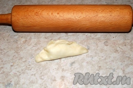 Защипывать пирожки с капустой из дрожжевого теста и укладывать на противень, застеленный бумагой для выпечки.