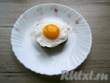 Бифштекс выложить на середину тарелки, сверху разместить жареное яйцо-глазунью.