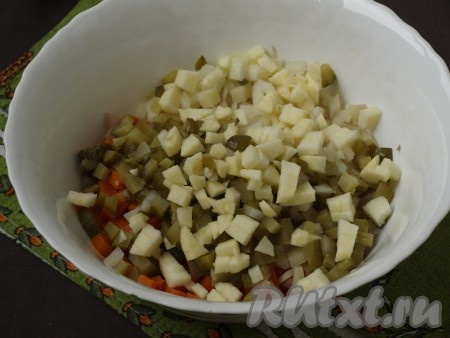 Нарезать кубиками маринованные огурцы и небольшую очищенную луковицу. Очистить яблоко и также нарезать его кубиками. Добавить огурцы, лук и яблоко к картошке и морковке.
