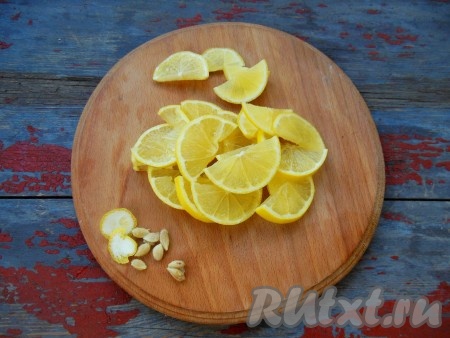 Лимон вымойте в теплой воде, выложите на дуршлаг и полейте сверху кипятком. Разрежьте лимон на две части, нарежьте каждую из частей на тонкие дольки. Удалите косточки из долек.
