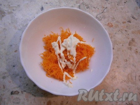 Очищенную сырую морковь натереть на мелкой терке в отдельную тарелку, добавить майонез и чеснок, пропущенный через пресс, тщательно перемешать получившуюся морковную смесь.

