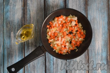 В разогретую сковороду влить растительное масло, выложить предварительно очищенные и нарезанные мелкими кубиками лук с морковью. Обжарить в течение 2-3 минут на среднем огне, периодически помешивая.
