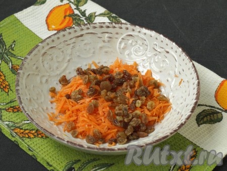 Сырую морковь очистить и натереть на тёрке. Изюм залить горячей водой, промыть и обсушить. Смешать изюм с морковью, немного посолить.
