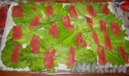 Рыбу нарезать тонкими пластинами и выложить на листья салата.
