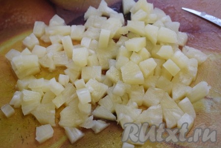Колечки консервированного ананаса нарезаем кубиками, выделившуюся жидкость сливаем.
