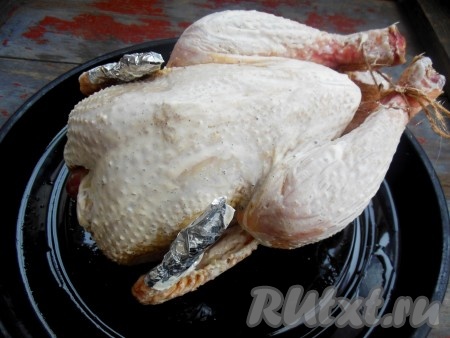 Силиконовой кисточкой смажьте курицу сверху сметаной и поставьте в заранее разогретую духовку.
