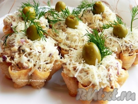 Посыпать тарталетки с рыбным салатом тертым сыром, украсить оливками и веточками укропа.