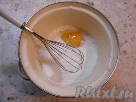 В кастрюлю влить молоко, добавить сырое яйцо и всыпать сахар.
